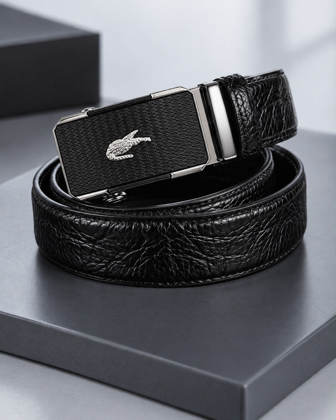 Black men's belt with crocodile-inspired textured strap and patterned silver-tone automatic-style buckle