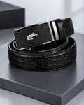 Black men's belt with crocodile-inspired textured strap and patterned silver-tone automatic-style buckle